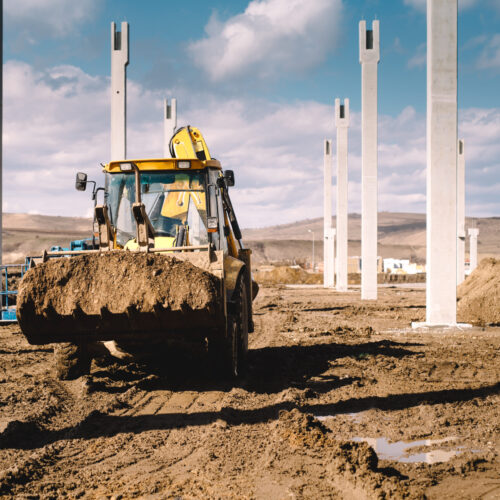 Industrial backhoe excavator and loader carrying earth and working on construction site